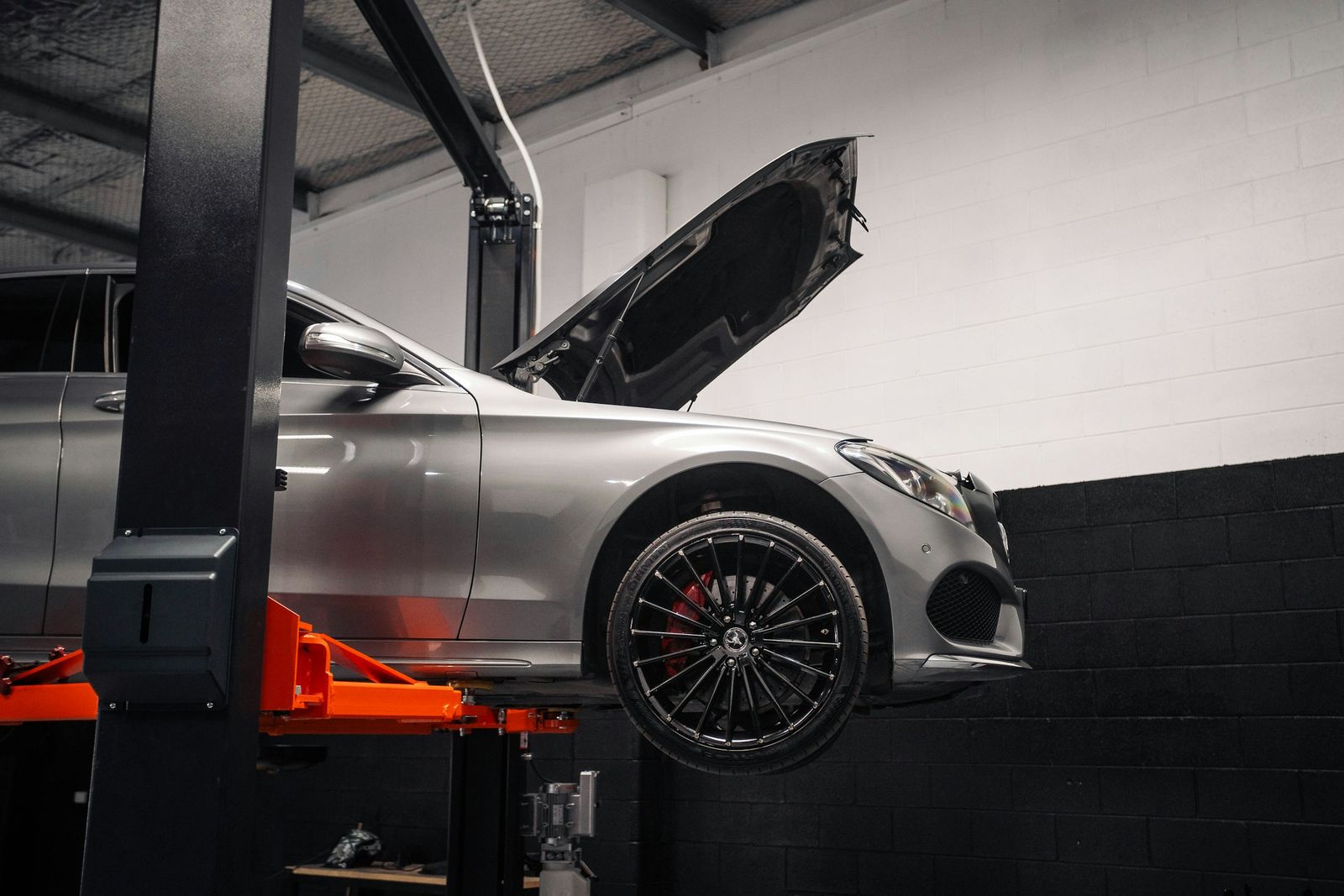 Silver car raised on a garage lift with its bonnet open